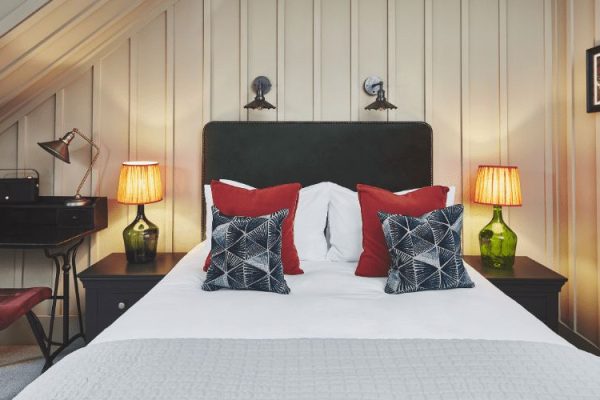 Intimate Woodland Room With Double Bed. Red and blue pillows laying on-top.