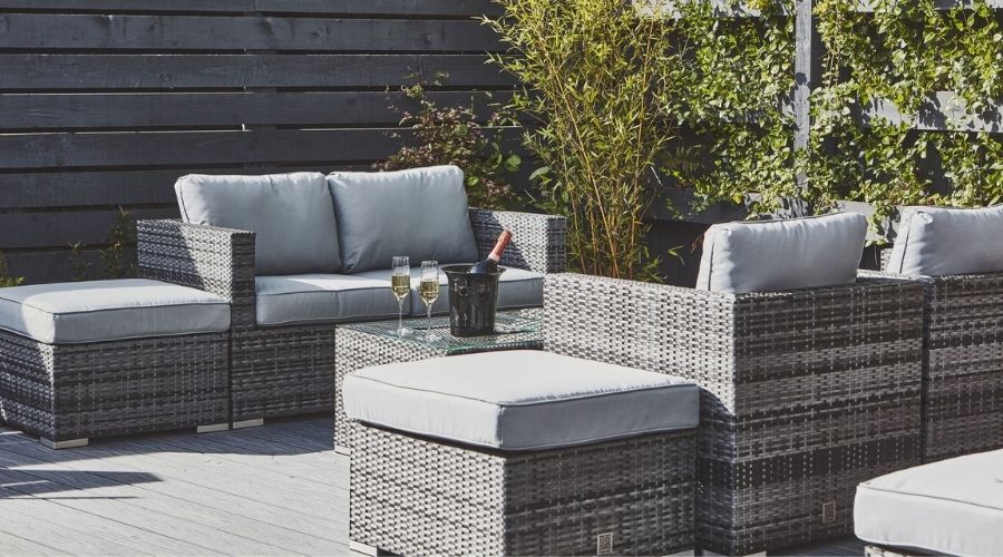 Grey outdoor furniture. Two glasses and a bottle of champagne are on the table.