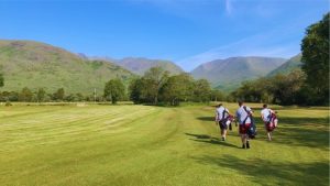 Dalmally golf course. Three golfers walking with mountains in the background.