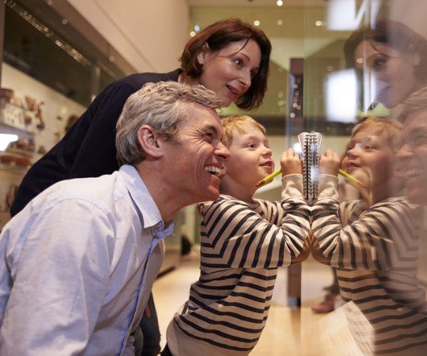 Man, woman, and child looking at something through glass